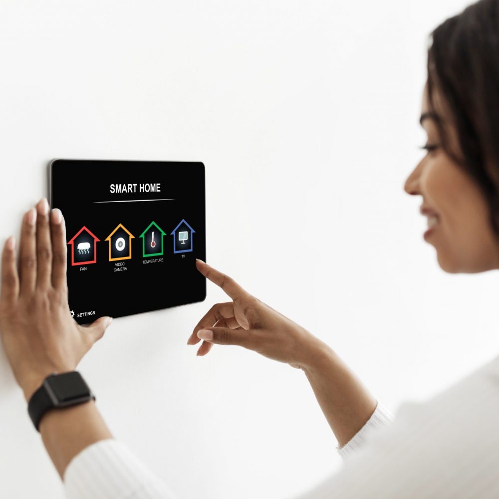 Modern smart home electronic systems concept. Black lady using smart home device, pushing button on pad automatic panel for managing various electronic processes at apartment, collage